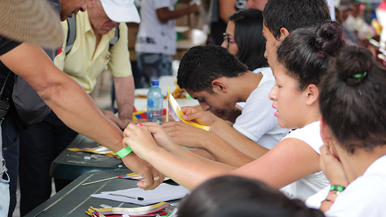 La ANT presente en comunidades indigenes. Persona poniendo manilla en evento.   