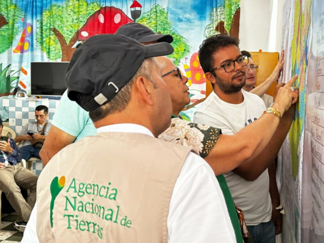 Funcionarios de la Agencia Nacional de Tierras y funcionarios de alcaldías municipales de Paicol y El Agrado en el Huila revisando el mapa.