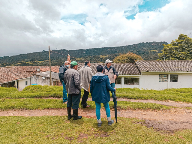 un-grupo-de-personas-parados-en-una-colina-mirando-una-casa