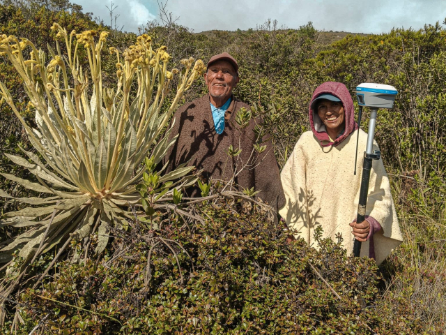 dos-personas-paradas-en-un-campo-con-una-planta