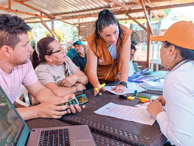 un-grupo-de-personas-sentadas-alrededor-de-una-mesa-con-computadoras