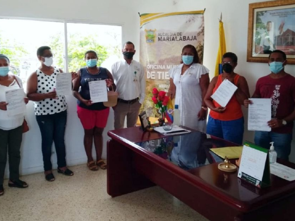 Grupo de personas mostrando los titulos de propiedad que se les entregaron