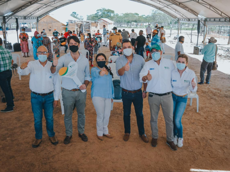 La Directora de la ANT, Myriam Martínez Cárdenas,  en compañía de cuatro funcionarios de la ANT y de un beneficiario de títulos posan en alineados, cada uno con su brazo levantado y pulgar arriba. De fondo varios integrantes de un resguardo de la comunidad Wayúu. 