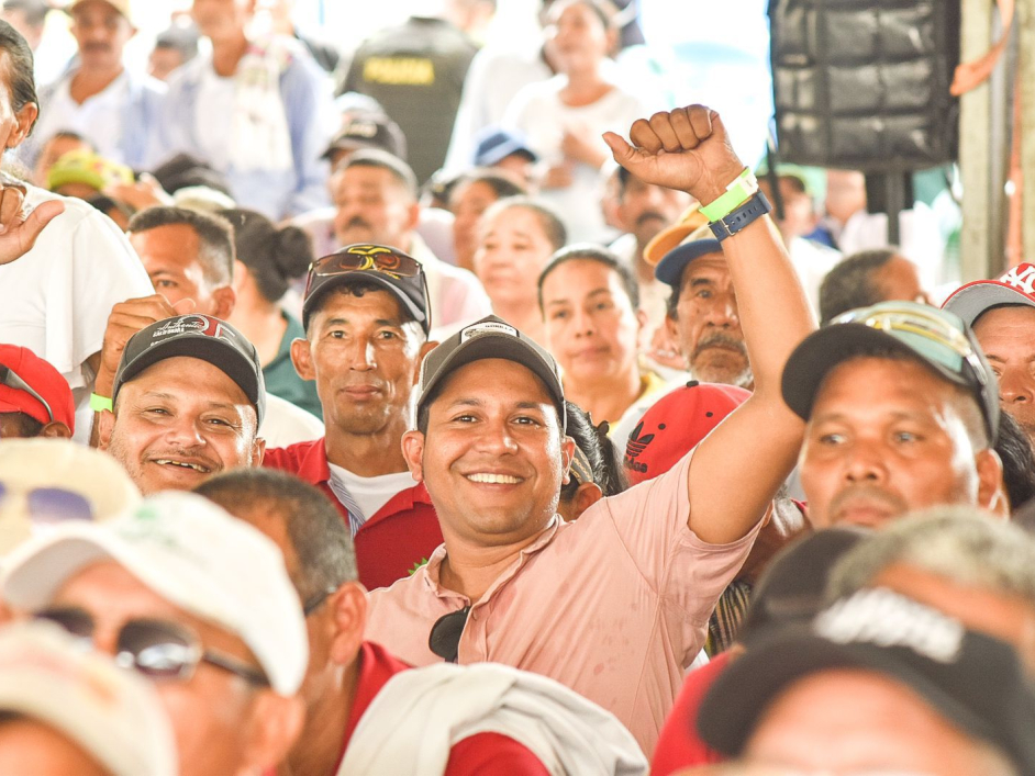 Asistentes al evento de entrega de tierras sonriendo.
