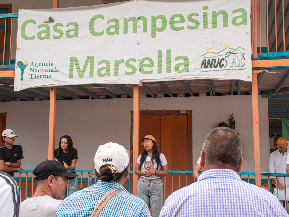 un-grupo-de-personas-parados-frente-a-una-bandera-que-dice-casa-campesina-la-marsella