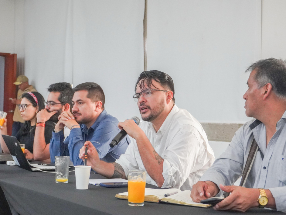 un-grupo-de-personas-sentadas-en-una-mesa-con-micrfonos