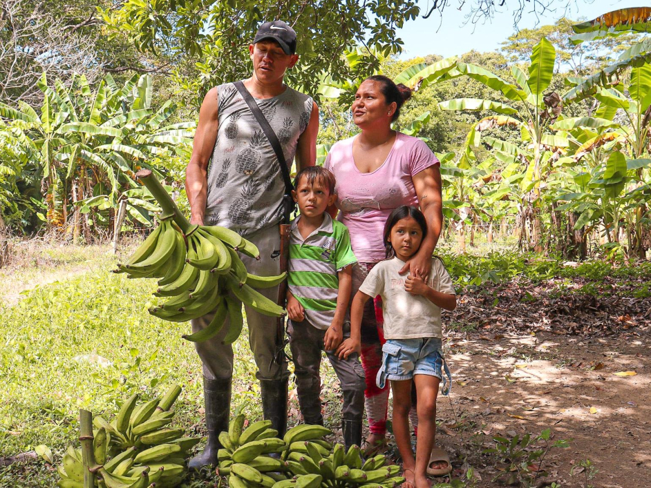 una-familia-parada-en-un-campo-con-un-racimo-de-pltanos
